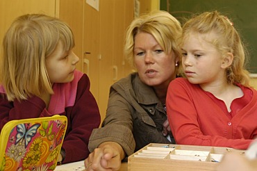 Zwei junge Schülerinnen hören Lehrerin zu