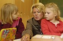 Zwei Schülerinnen hören Lehrerin aufmerksam zu