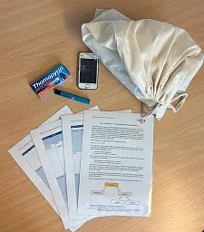 Leinenbeutel mit beispielhaften Inhalten, wie Handy, Medikamentenpackung, Vape und einer methodischen Anleitung