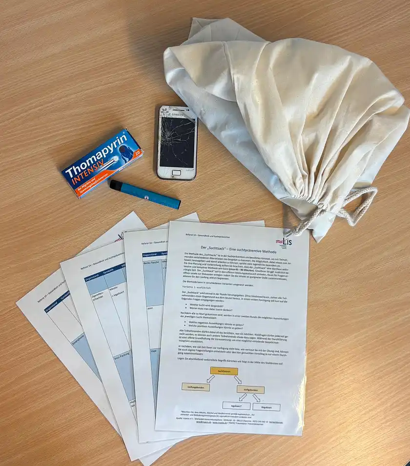 Leinenbeutel mit beispielhaften Inhalten, wie Handy, Medikamentenpackung, Vape und einer methodischen Anleitung