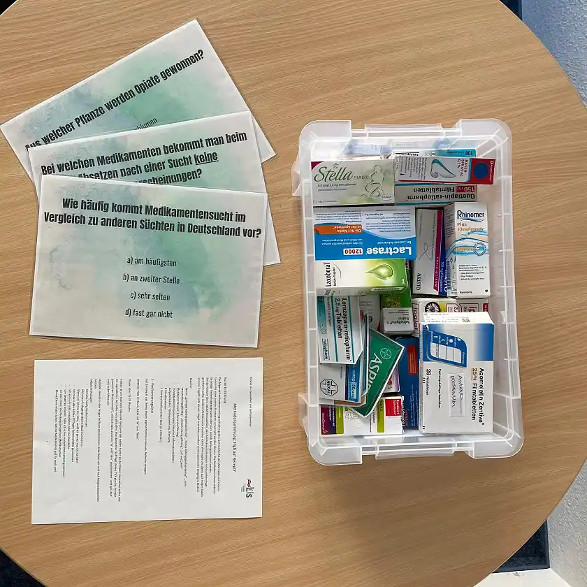 Plastikkiste mit unterschiedlichen Medikamentenverpackungen, Aktionskarten und Anleitung