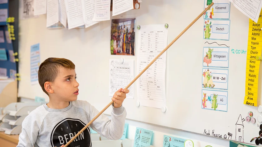 Junge erläutert Tagesplan im Klassenzimmer