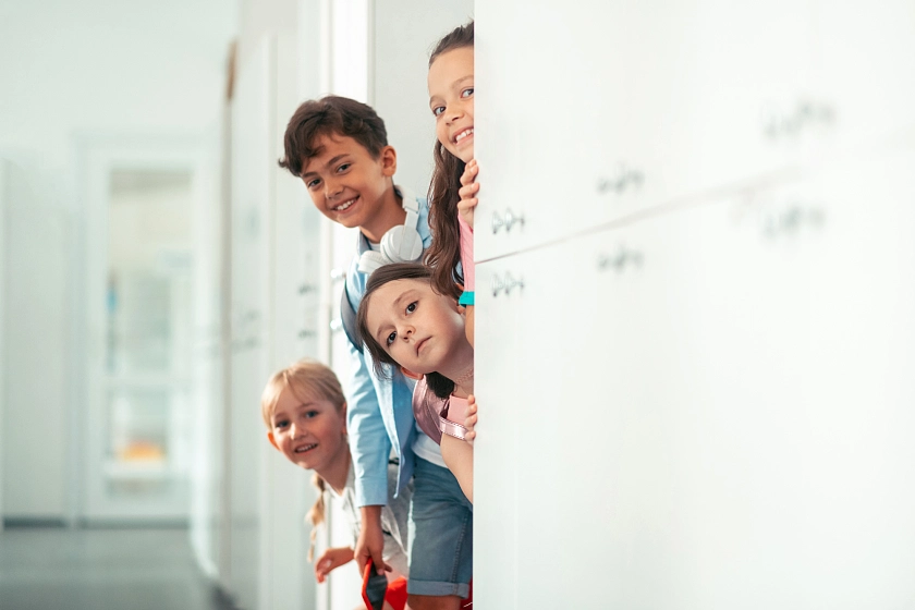 Schulkinder schauen um die Ecke