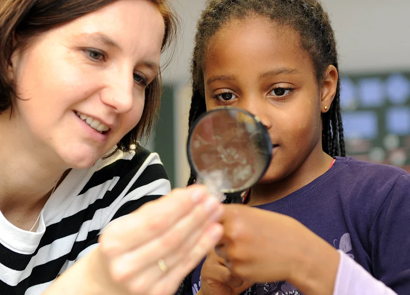 Bild 4 Stiftung Kinder forschen, Personen gucken etwas durch Lupe an 