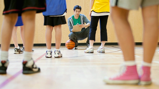 Lehrkraft in einer Sporthalle unterrichtet Kinder