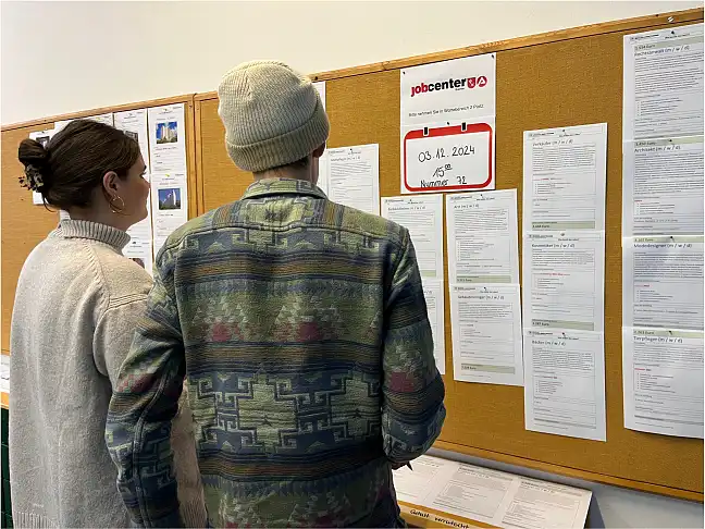 Zwei Lehrkräfte informieren sich an Aushängen