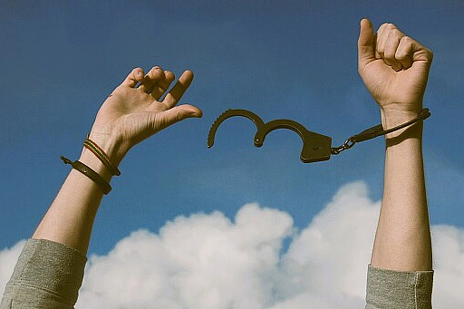 Hände mit geöffneten Handschellen als Symbol für Befreiung