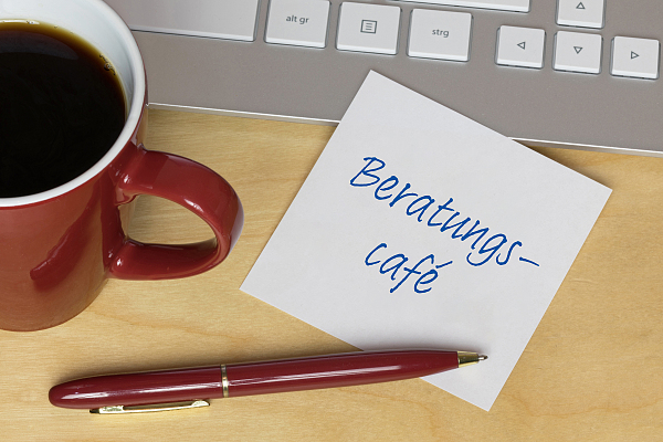 Stift, Kaffee und ein Blatt Papier mit der Aufschrift Beratungscafe