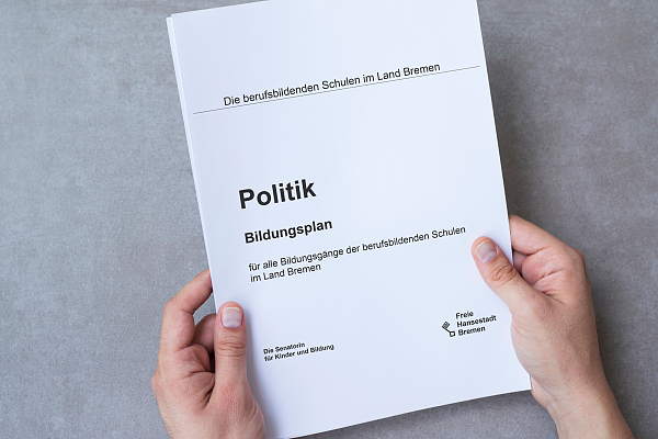 Hände halten den Bildungsplan Politik für Berufsbildende Schulen