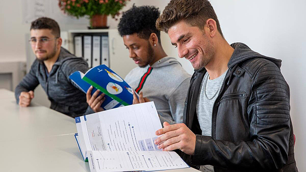 Junge Erwachsene arbeiten mit DaZ-Material der SchlaU-Werkstatt