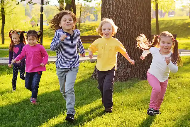 Kinder laufen schwungvoll über Wiese