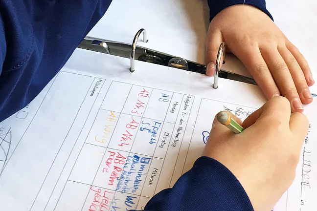 Kind füllt KomPoLei-Bogen aus