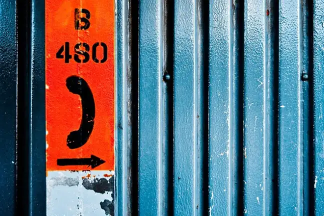 Blauer Container, rotes, abgenutztes Schild mit Hinweis auf ein Telefon (amerikanisch)