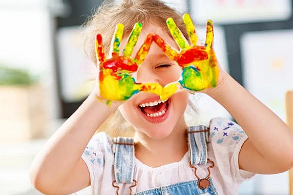 Lächelndes Kind hält Hände hoch zur Bildungsinitiative