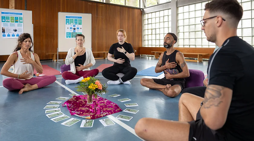 Personenkreis in Sporthalle in sitzender Position