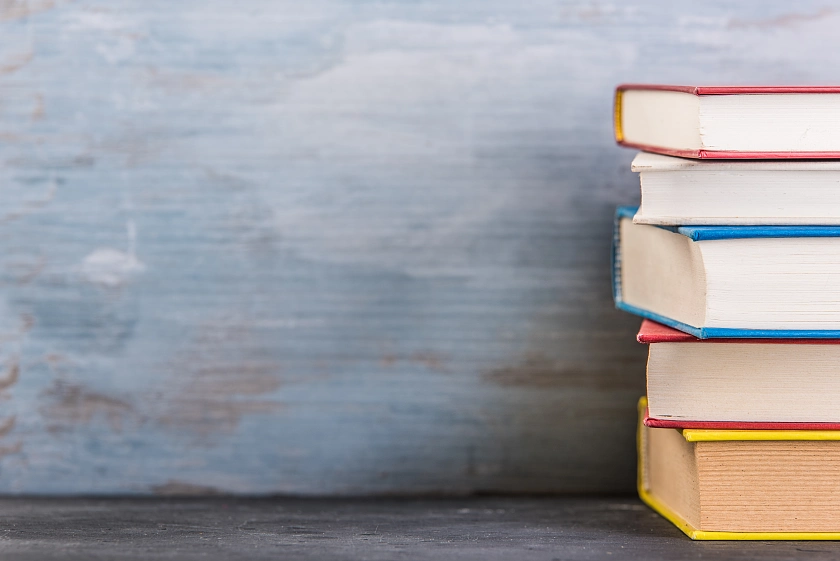 Es sind fünf Bücher aufeinander gestapelt am rechten Bildrand abgebildet