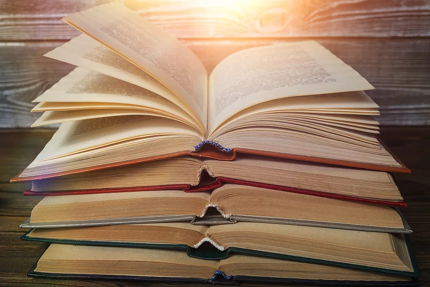 Es werden fünf Bücher abgebildet, die jeweils aufgeschlagen übereinander liegen