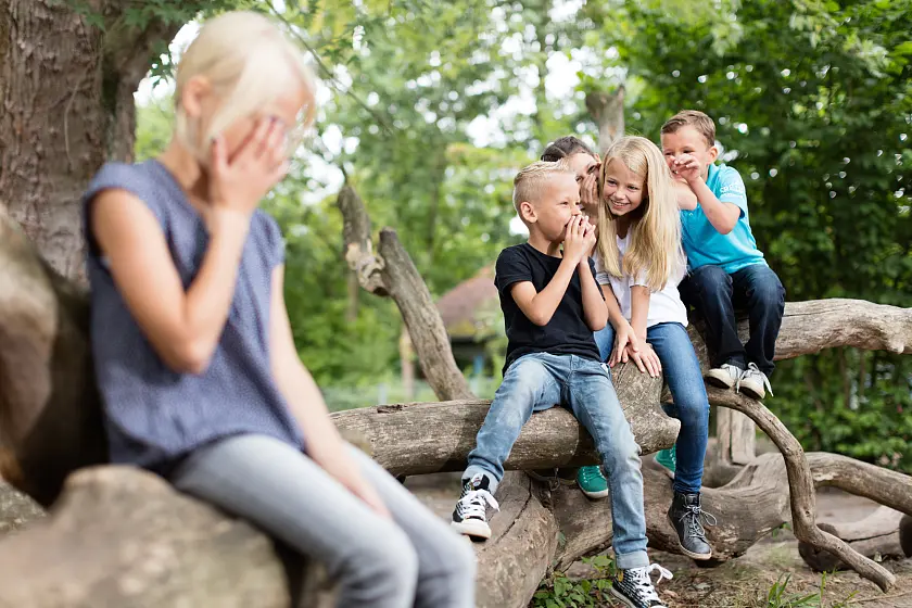 Kinder tuscheln über ein Mädchen