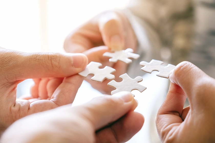 Hände fügen ein Puzzle zusammen